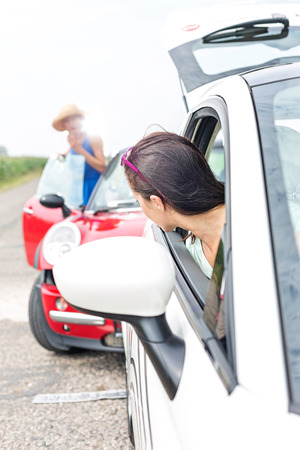Woman looking at female crashing car on roadの写真素材