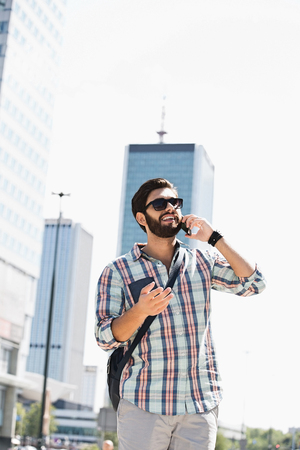 Happy man looking away while using cell phone in cityの写真素材