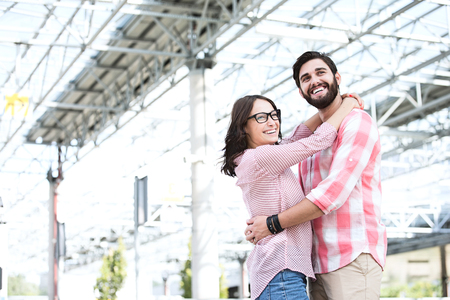 Happy couple looking away while embracing outside buildingの写真素材