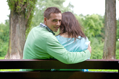 Portrait of young man with girlfriend sitting on benchの写真素材