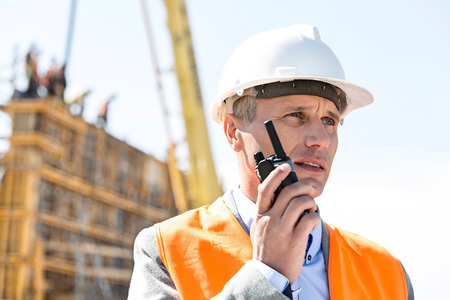 Confident supervisor using walkie-talkie at construction siteの写真素材