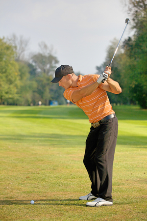 Young man swinging golf clubの写真素材