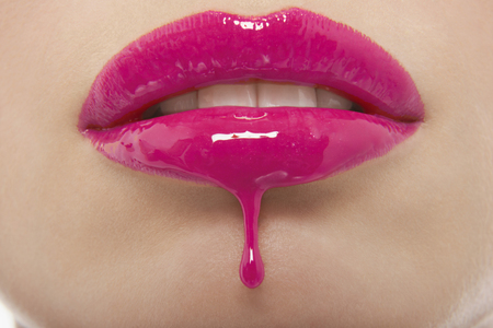 Detail shot of pink lipgloss dripping from woman's lipsの写真素材