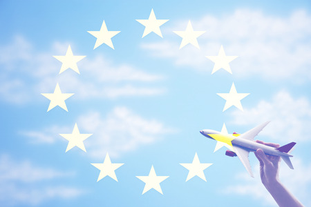 Person holding a toy plane flying in from of EU Flagの写真素材