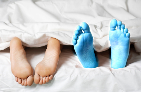 Closeup of a couple lying in bed barefeetの写真素材