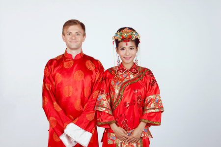 Mixed Race Bride and Groom in Studio wearing traditional Chinese wedding outfitsの写真素材