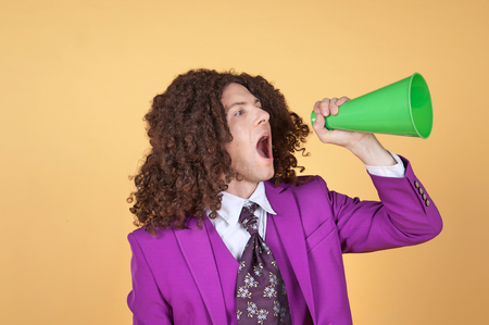 Caucasian man with afro wearing Purple Suit shouting from a coneの写真素材