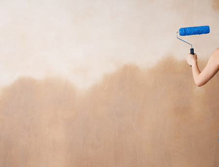 Rear view of a cropped woman painting wall with paint rollerの写真素材