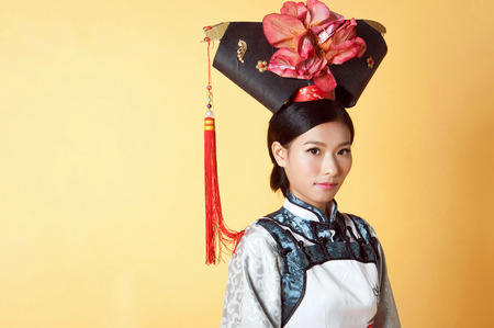 Beautiful Chinese Woman wearing traditional outfit against yellow backgroundの写真素材