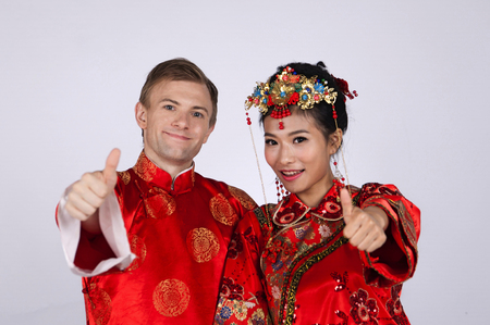 Mixed Race Bride and Groom in Studio wearing traditional Chinese wedding outfitsの写真素材