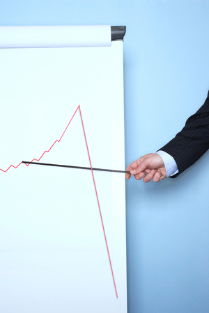 Businessman pointing at graph on flip chart against blue wallの写真素材