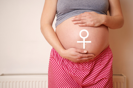 Midsection of an expectant woman touching belly with female symbol on bellyの写真素材