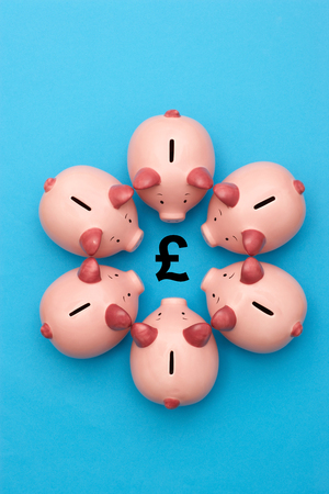 Piggy banks on blue background surrounding a GBP Symbolの写真素材