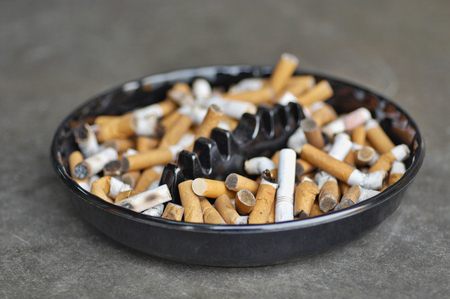Full ashtray of cigarettes on table, close-upの写真素材