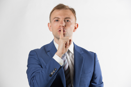 Businessman with finger over lipsの写真素材