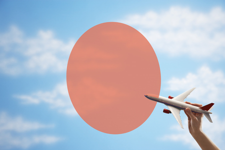 Toy plane flying in front of Japanese flagの写真素材