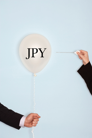 Cropped hands holding needle and popping balloon with JPY written in textの写真素材