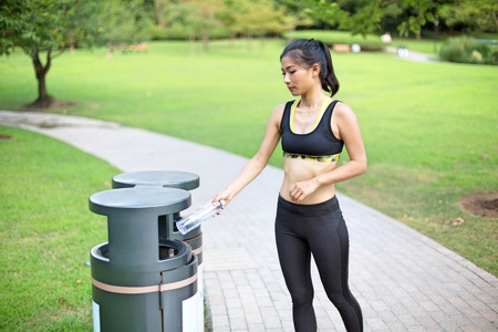 Beautiful asian woman recycling in park after her runの写真素材