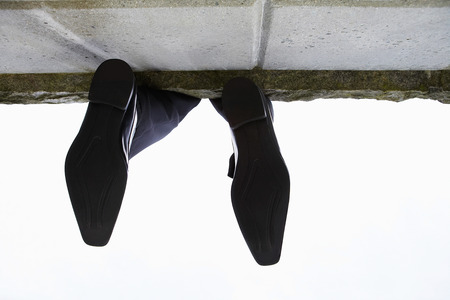 Feet dangling over wall, low angle viewの写真素材