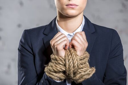 Midsection of young businesswoman standing with tied hands at officeの写真素材
