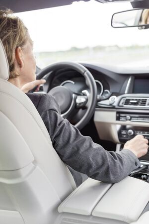 Female executive driving car during business tripの写真素材