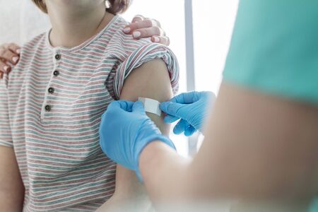 Nurse applying bandage on boy arm at hospitalの写真素材
