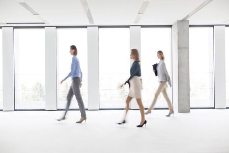 Defocused image of businesswomen walking in empty workspaceの写真素材