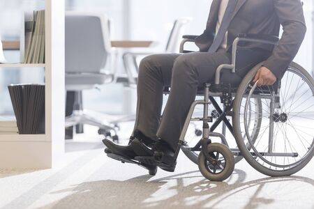 Low angle view of disabled businessman on wheelchair at modern officeの写真素材