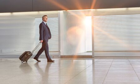 Mature businessman walking with his suitcase in the airportの写真素材