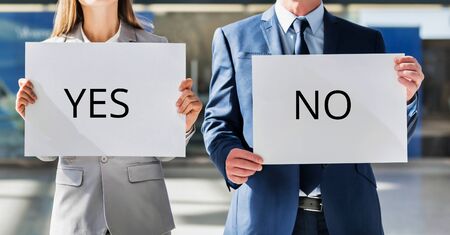 Business people standing while holding white YES or NO placardの写真素材