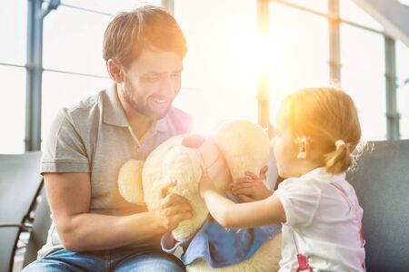 Portrait of man playing with her daughter while sitting and waiting for boarding in airportの写真素材
