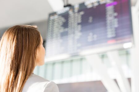 Businesswoman looking at flights display screen in airportの写真素材
