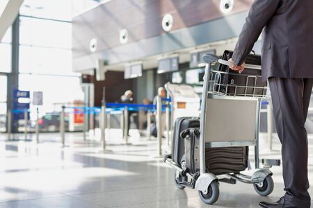 Mature businessman pushing baggage cart for check in at airportの写真素材