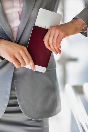 Portrait of young attractive businesswoman holding her passport and boarding pass in airportの写真素材