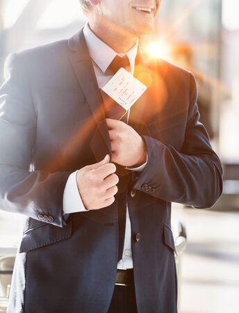 Portrait of mature attractive businessman taking out his passport from his suit in airportの写真素材