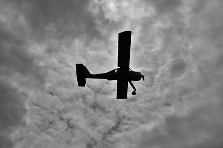 Old plane is flying in the sky. Black & white.