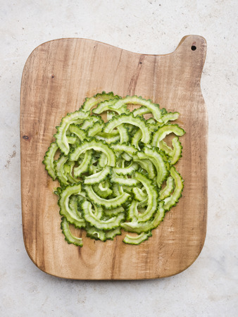 A pile of Bitter melon slices on chopping block.の写真素材