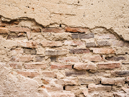 Old brick wall with cracked stucco layer.の写真素材