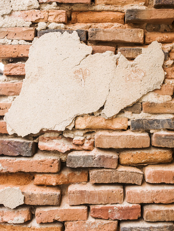Old brick wall with cracked stucco layer.の写真素材
