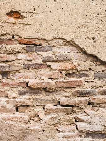 Old brick wall with cracked stucco layer.の写真素材