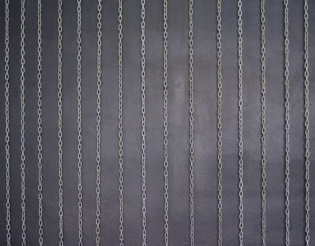Chains is stretched on black cement wall.