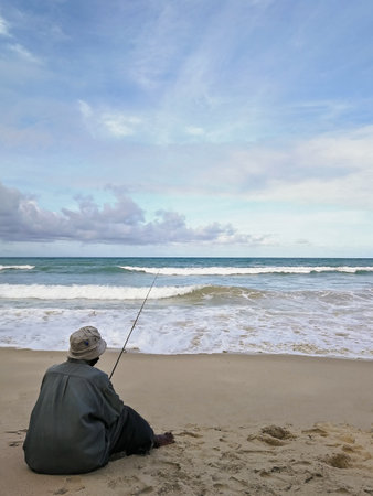 A man is fishing on the beach during the dayの写真素材