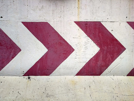 Row of red direction arrow stripes painted on concrete wall, warning arrow road sign pointing turn right, wide banner backgroundの写真素材