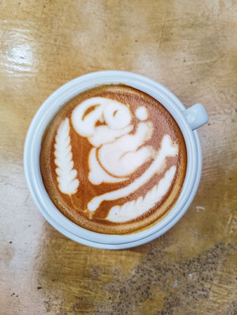Hot coffee latte with latte art milk foam in cup mug on wood desk, top view.の写真素材