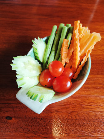 A bowl of fresh cucumbers, tomatos, string beans and carrots as a side dish (Selective Focus)の写真素材