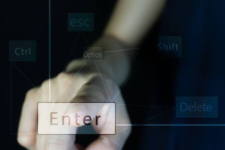 A business person finger point and click at the transparent enter keyboard on the digital screen. There are other button such as alt , esc, delete and shift and option on the beautiful dark background.の写真素材