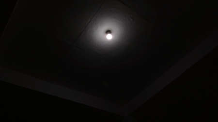 A white light bulb turned on during night time in the dim roomの写真素材
