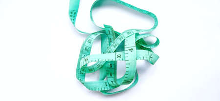 Old wrinkled green rubber tape measure with negative space. Rubber tape measure isolated on the gray...