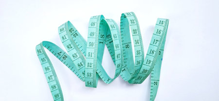 Old wrinkled green rubber tape measure with negative space. Rubber tape measure isolated on the gray...