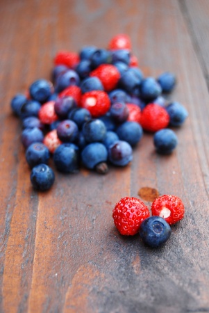 Delicious forest berries on wooden table. Shallow dof, vertical formatの写真素材